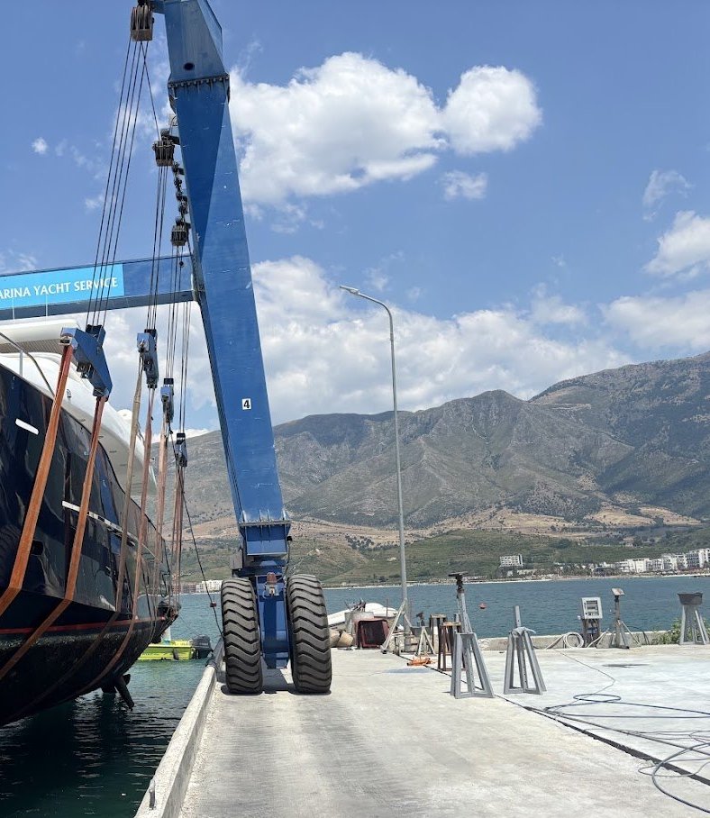 Kolona dhe rrotat e travel lift-it në kalatë, me malet përtej gjirit.