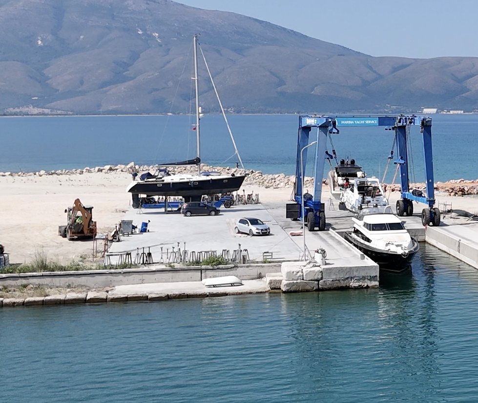 Një jaht me vela mbi kavaletë në sheshin e betonuar të kantierit.